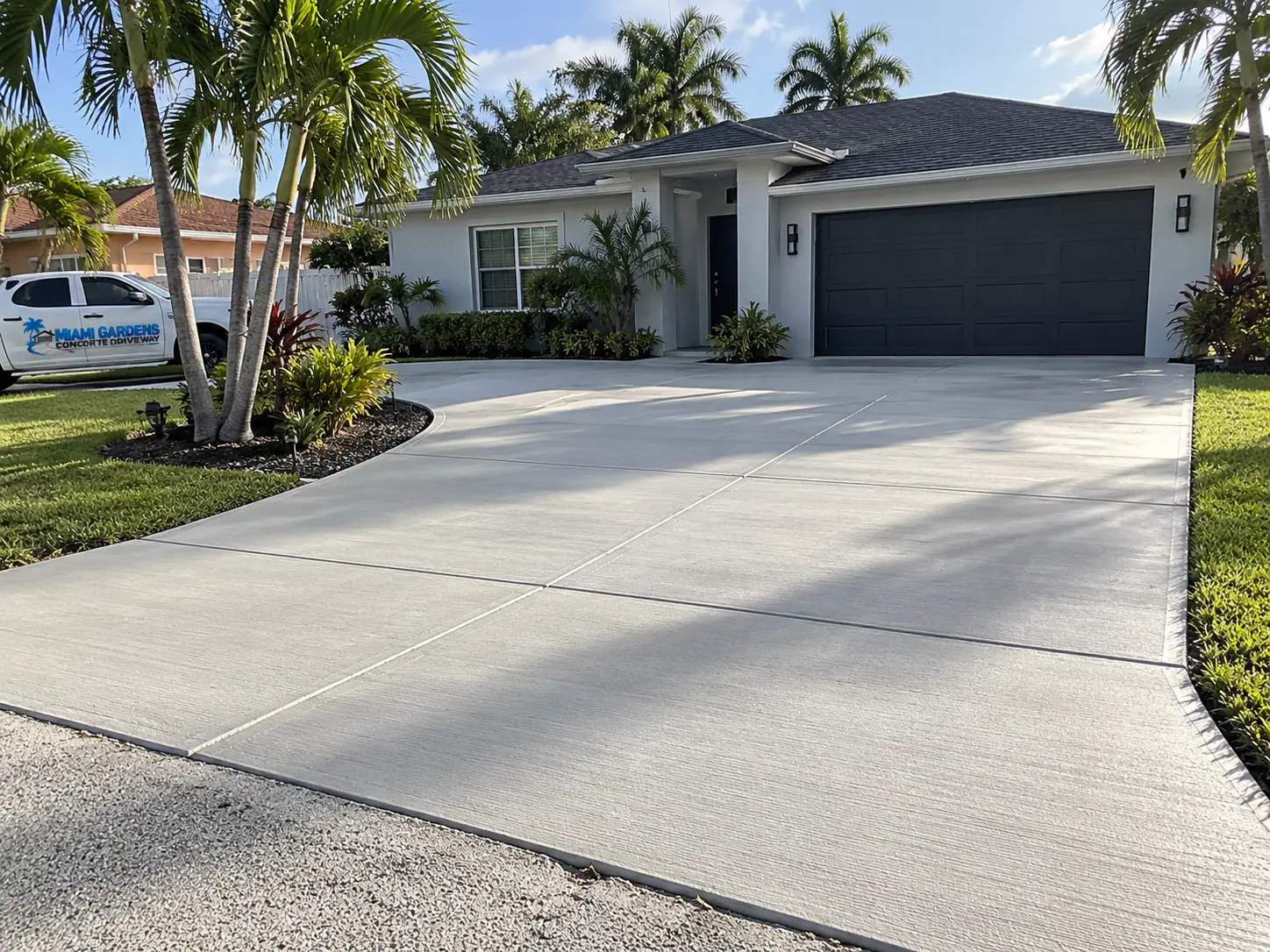 Completed broom-finish concrete driveway with clean control joints leading to a two-car garage